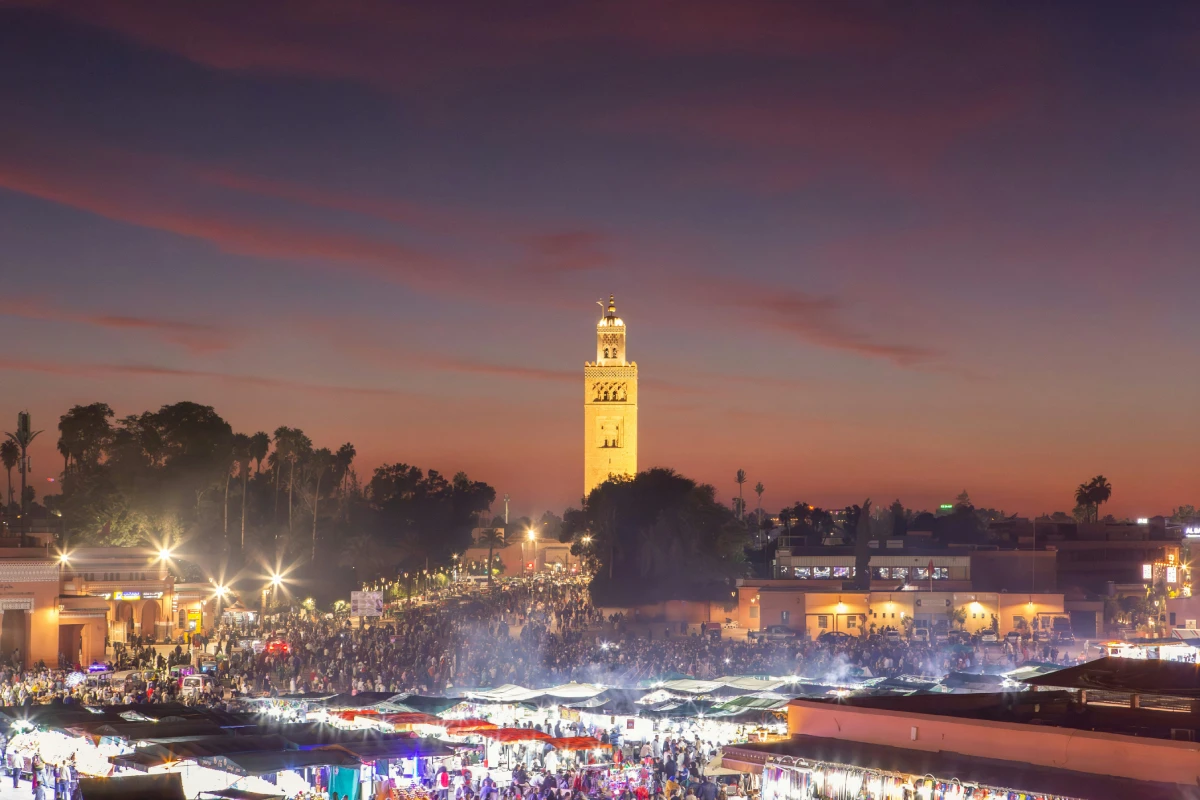 Bustling Jemaa el-Fnaa Square in Marrakech filled with food stalls, performers, and market vendors at sunset