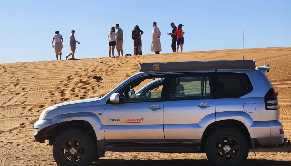 Group of tourists with guide next to 4x4 vehicles in Merzouga desert
