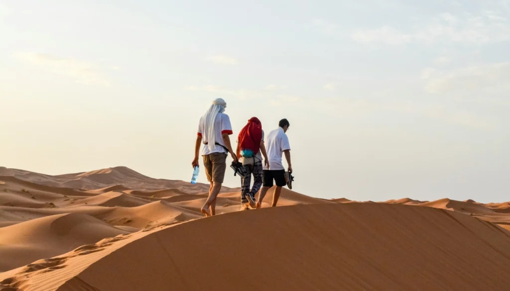 Guided hiking group walking across Merzouga sand dunes