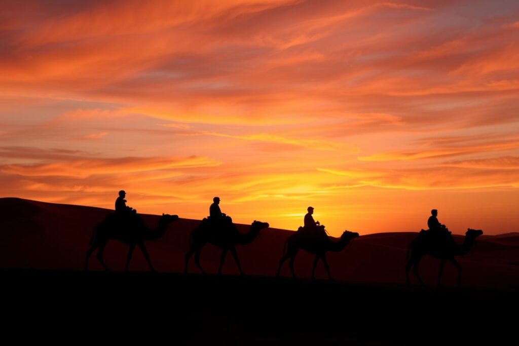 Silhouette of camels and riders against a colorful Merzouga sunrise