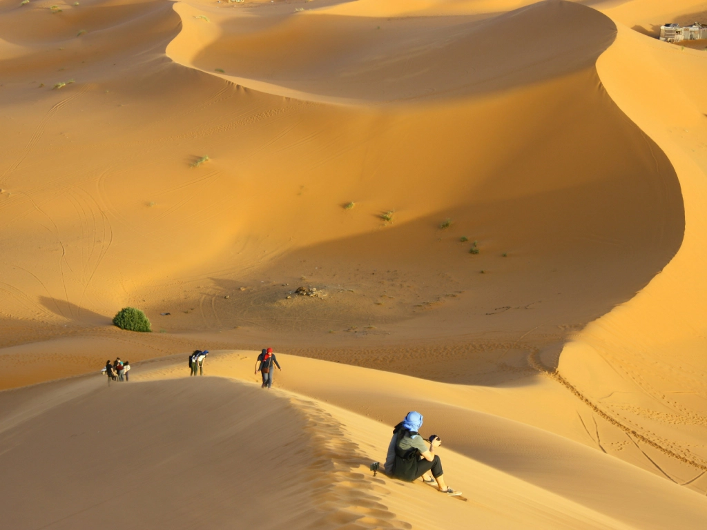 Sunrise over Merzouga desert with silhouette of desert camp