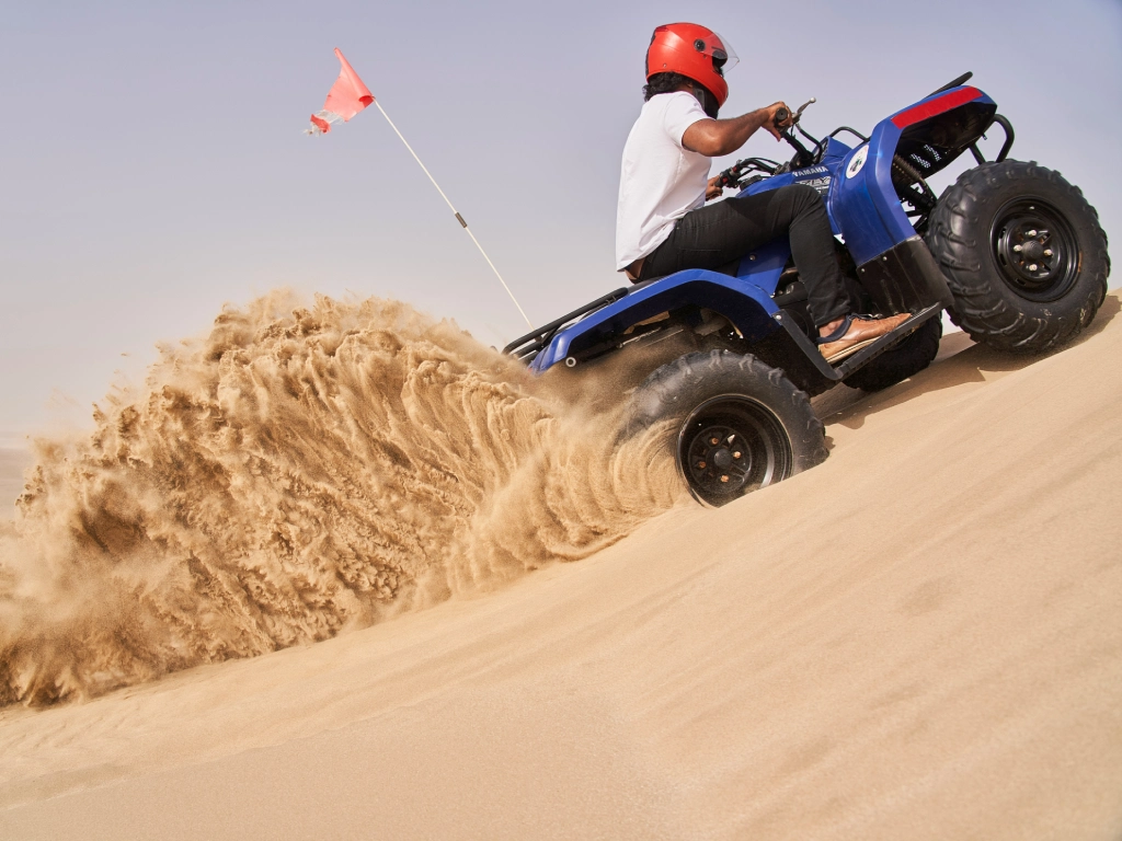Merzouga ATV quad biking across golden sand dunes in the Sahara Desert