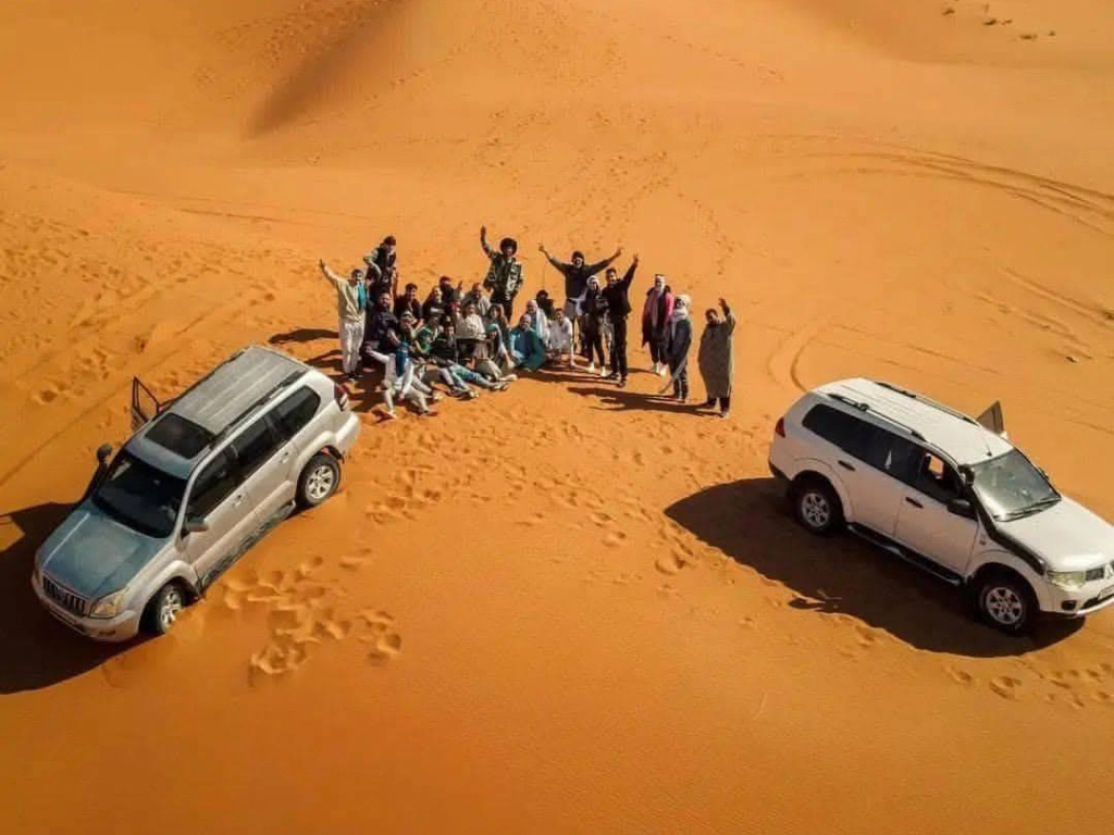 Tourist with appropriate desert gear next to 4x4 vehicle in Merzouga