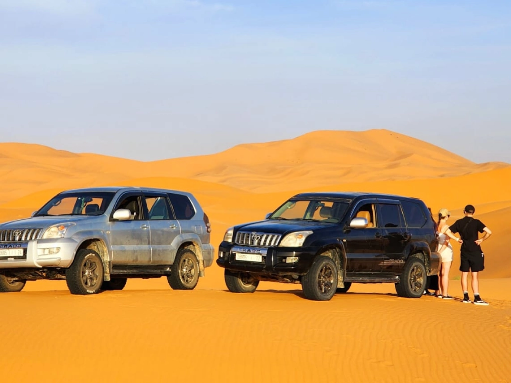 Tourist-with-appropriate-desert-gear-next-to-4x4-vehicle-in-Merzouga