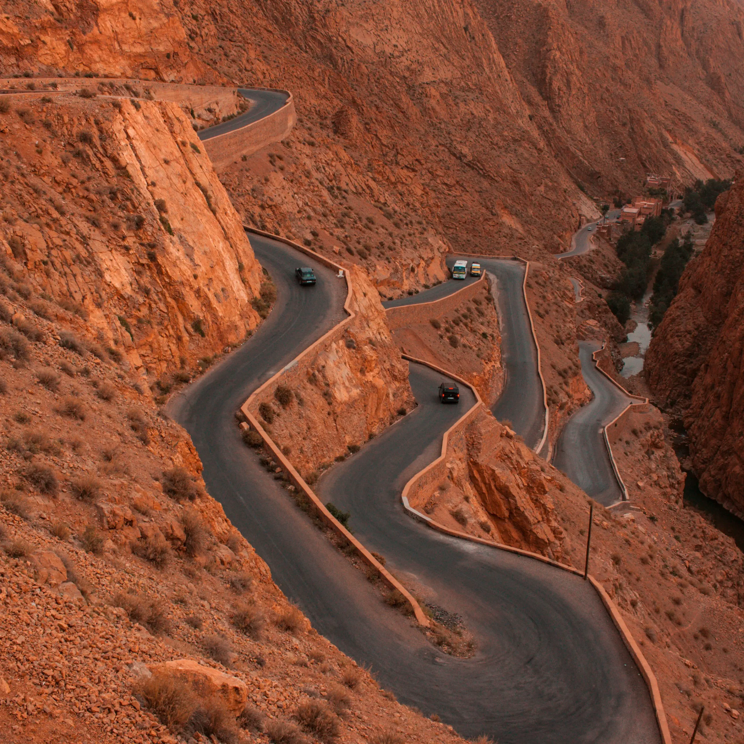 4 days desert tour from Marrakech — aerial view of Dades Gorge winding road with hairpin bends through orange limestone cliffs Morocco