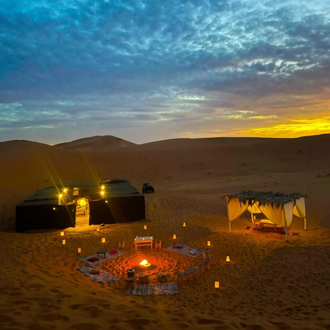 3 days desert tour from Marrakech — traditional Berber luxury desert camp at night with candles and campfire Merzouga Erg Chebbi Sahara Desert Morocco